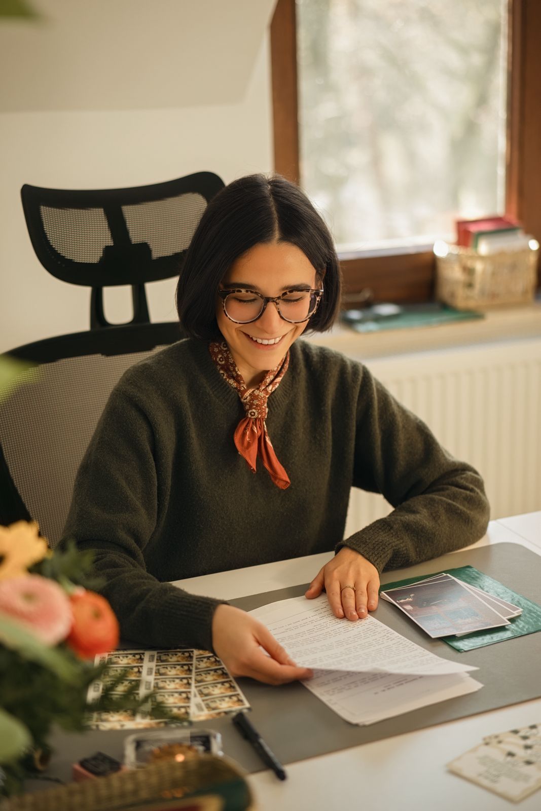 Woman sitting at a desk with papers, smiling.
