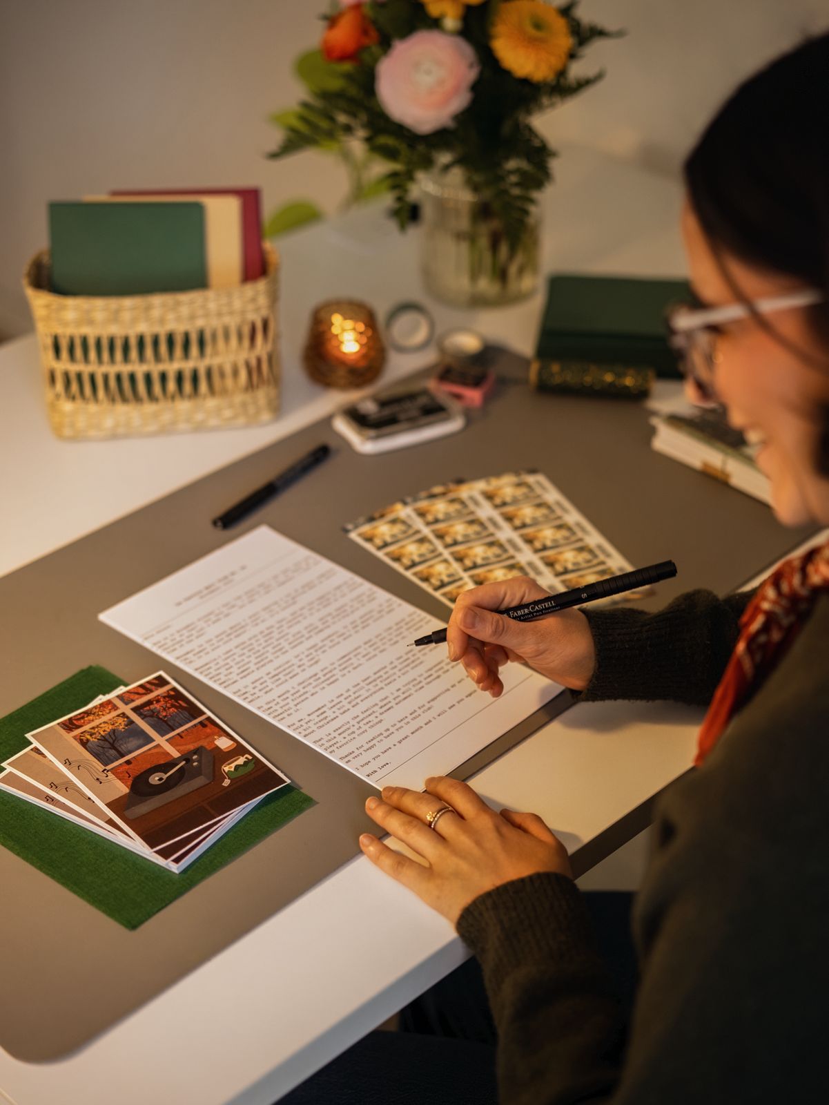 Person filling out a letter with photos and stationery on a table
